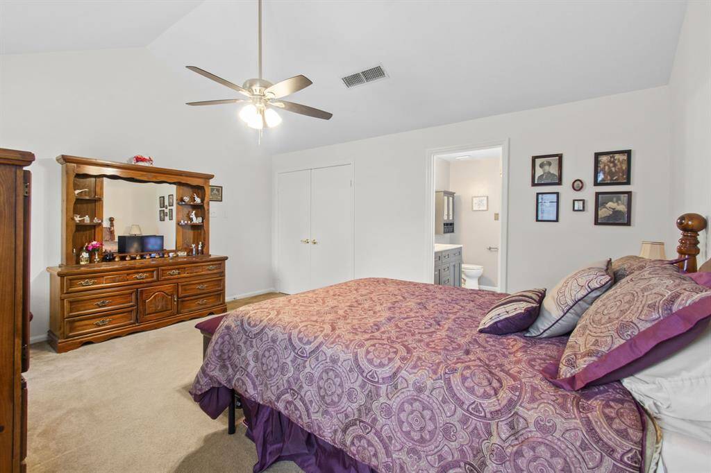 Spacious primary bedroom featuring a cozy atmosphere, vaulted ceiling, and direct access to the primary bathroom.