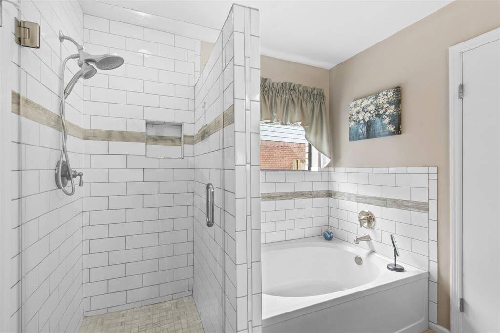 Luxurious primary suite featuring a relaxing tub and a spacious walk-in shower.