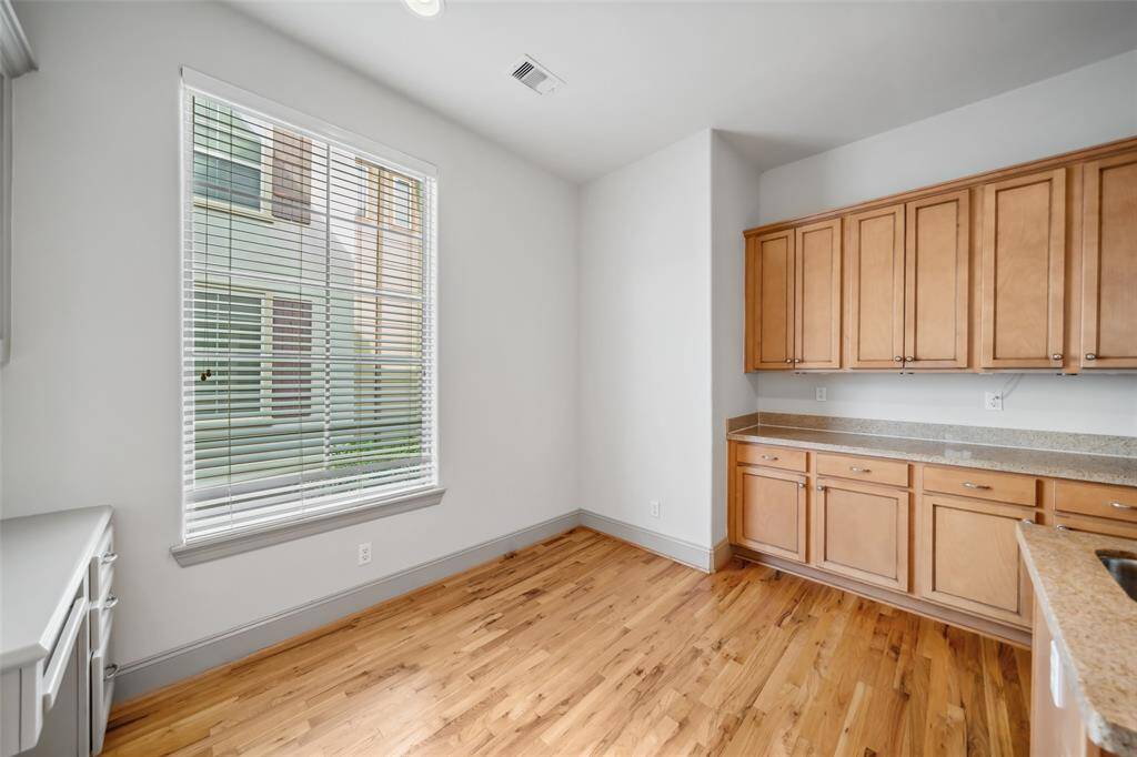 This inviting living room boasts hardwood floors, a cozy fireplace, and abundant natural light. The space is perfect for entertaining with a spacious sectional, modern coffee table, and built-in shelving with a large TV.