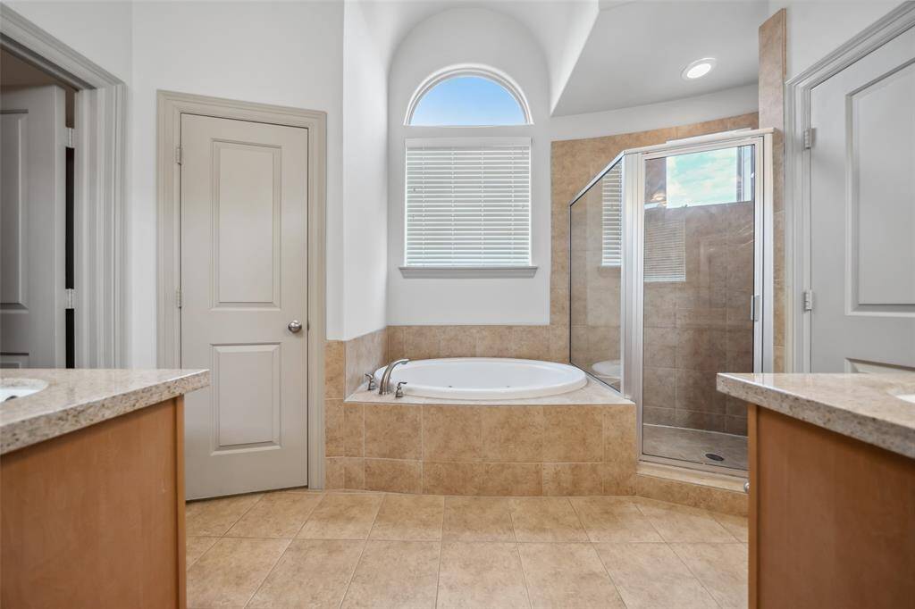 This bright, spacious home office features a high ceiling, hardwood floors, and ample natural light from two windows. It includes a modern desk setup with dual monitors, an ergonomic chair, and a stylish wood cabinet, perfect for productivity and comfort.