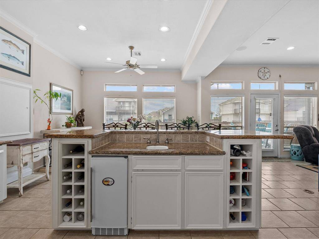 The kitchen island serves as a central hub for entertaining, featuring a built-in sink, beverage refrigerator, and wine racks.