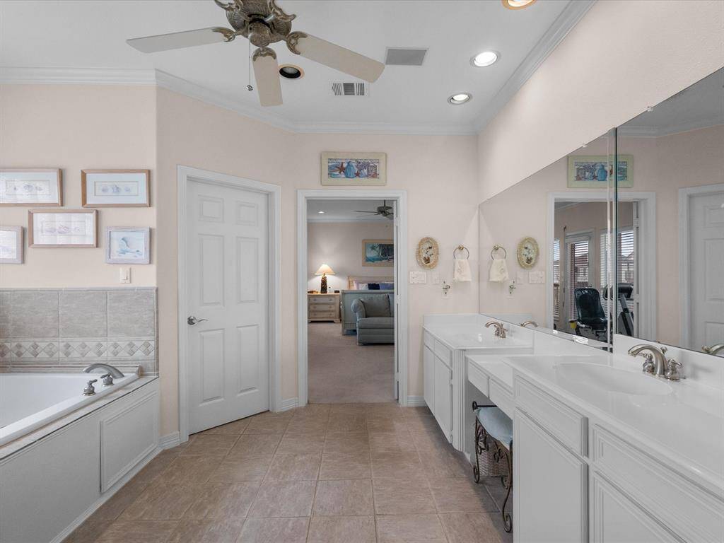 The luxurious primary bathroom features a double vanity with ample counter space and storage, along with a large mirror.