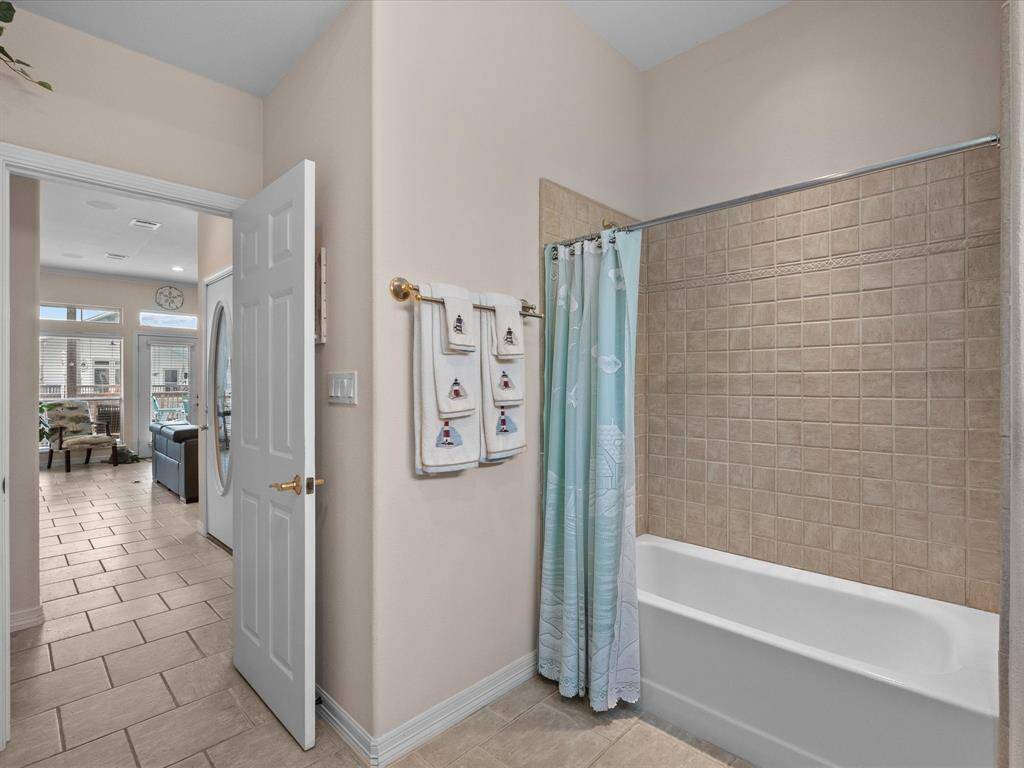 This main level bathroom features neutral-toned tiling, providing a clean and functional space.