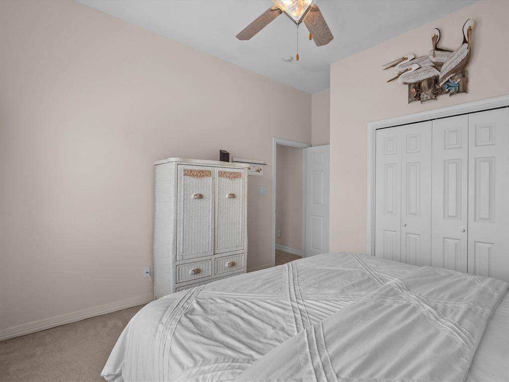 This spacious bedroom offers convenient storage with a double-door closet. The room is equipped with a ceiling fan for comfort, and neutral-toned walls.