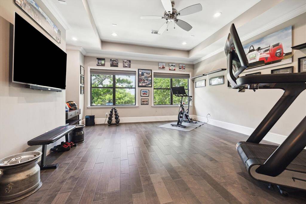 This photo showcases a spacious second floor game room with wood flooring.  Large windows provide natural light and a view of greenery, creating an inviting flexible space.