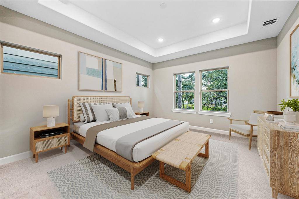 Tray ceilings, abundant windows, and plush carpeting create a serene escape in the spacious primary bedroom.