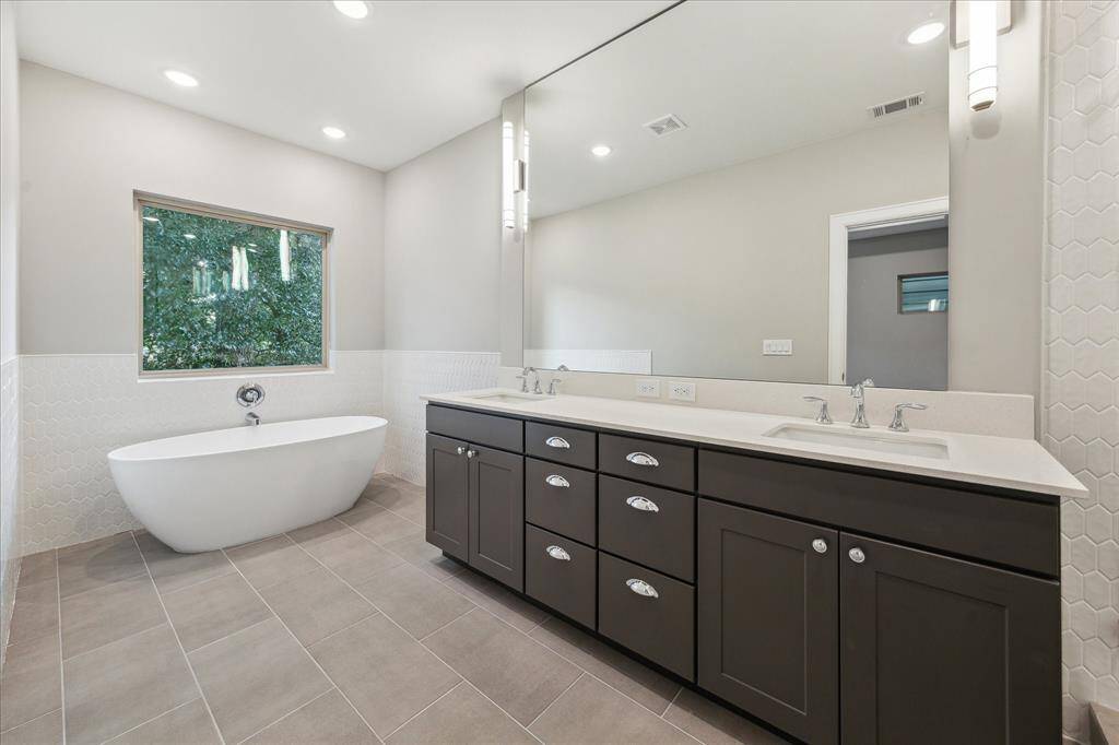 Dual vanities, polished chrome, and a freestanding soaking tub create a true primary suite experience.
