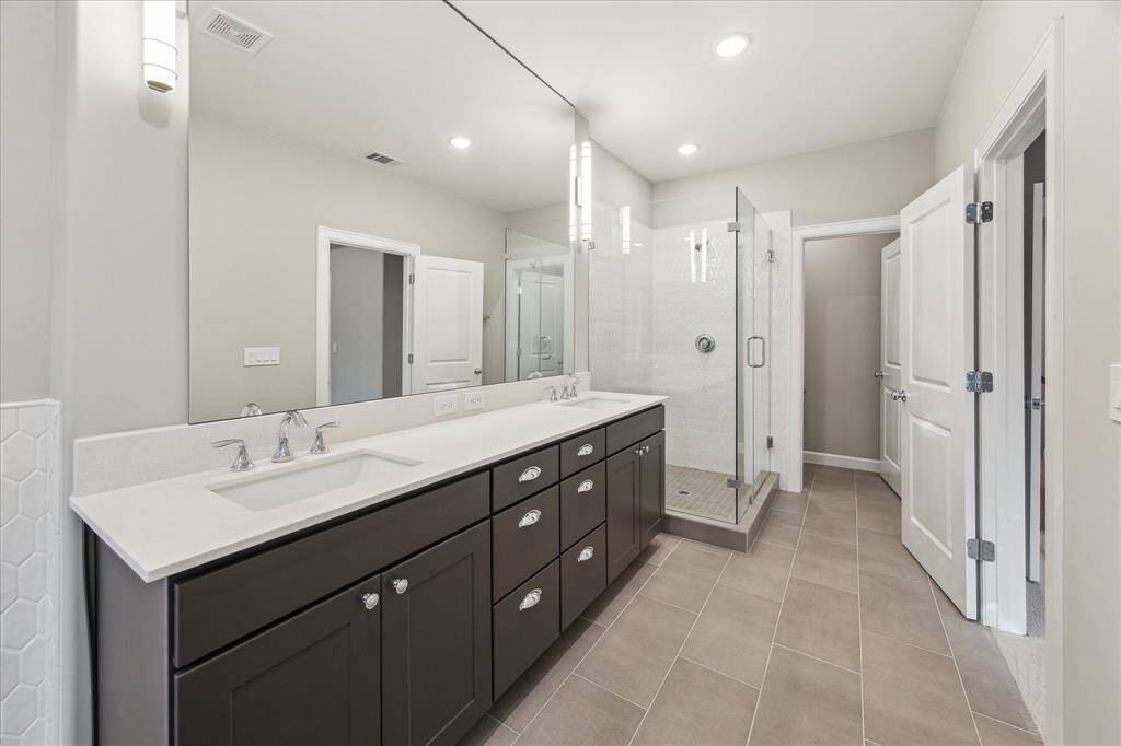 Step into a generous walk-in shower with frameless glass and designer tile for a polished, contemporary finish.