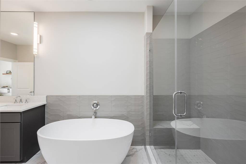 Dual vanities, polished chrome, and a freestanding soaking tub create a true primary suite experience.
