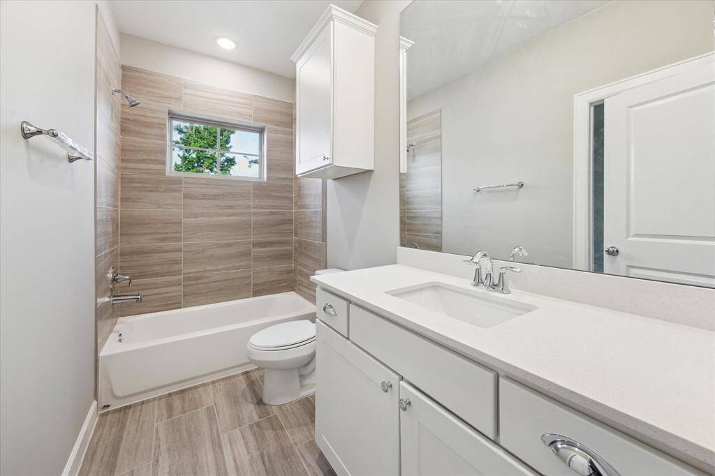 Wood-look tile and warm natural tones create a calming space with designer finishes and practical storage.