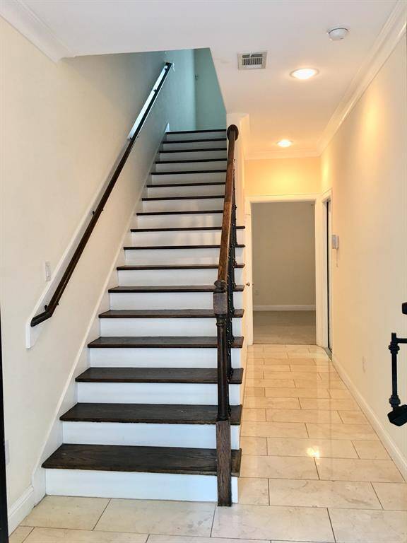 Entry foyer, stairway leads to second floor open space dining/kitchen/living with guest bath. Going straight leads to first floor guest bedroom and on the right the door goes to two car parking garage with an extra storage room.