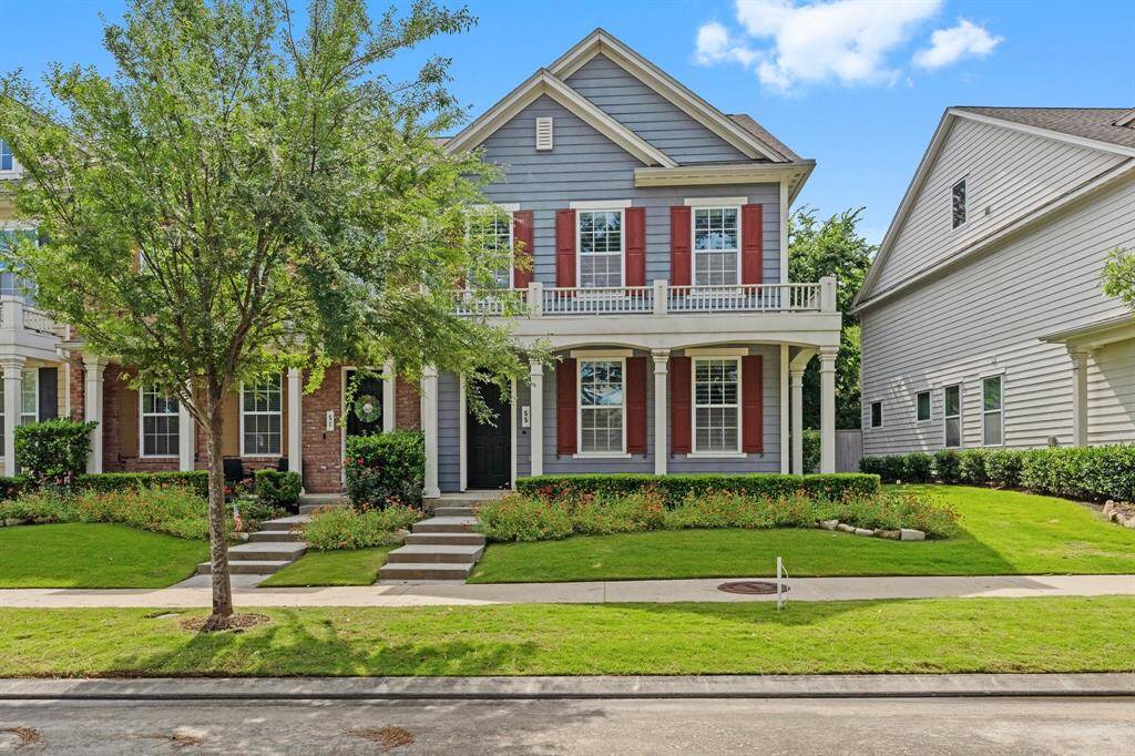 Charming two-story home with inviting double front porches, classic red shutters, and beautifully maintained landscaping in a desirable neighborhood.