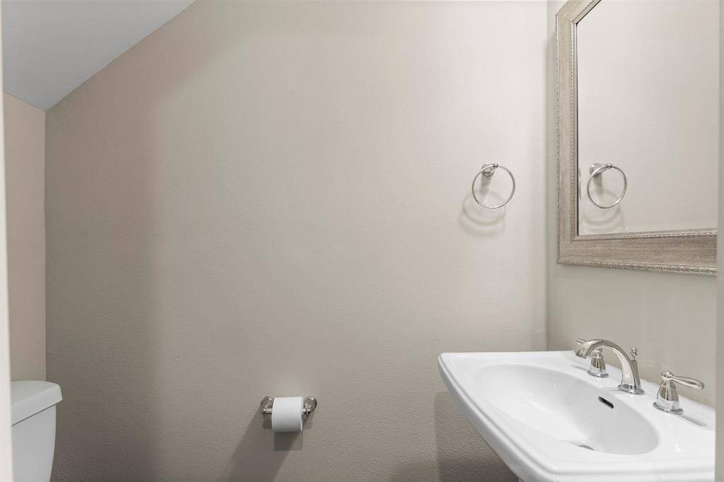 Charming half bath with pedestal sink, brushed nickel fixtures, and neutral tones perfect for guests.