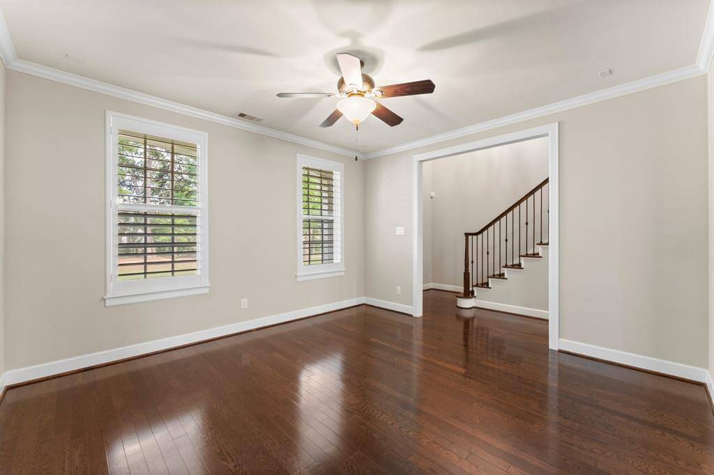 This bright and airy flex space offers hardwood flooring, crown molding, and views of the backyard through plantation-shuttered windows.
