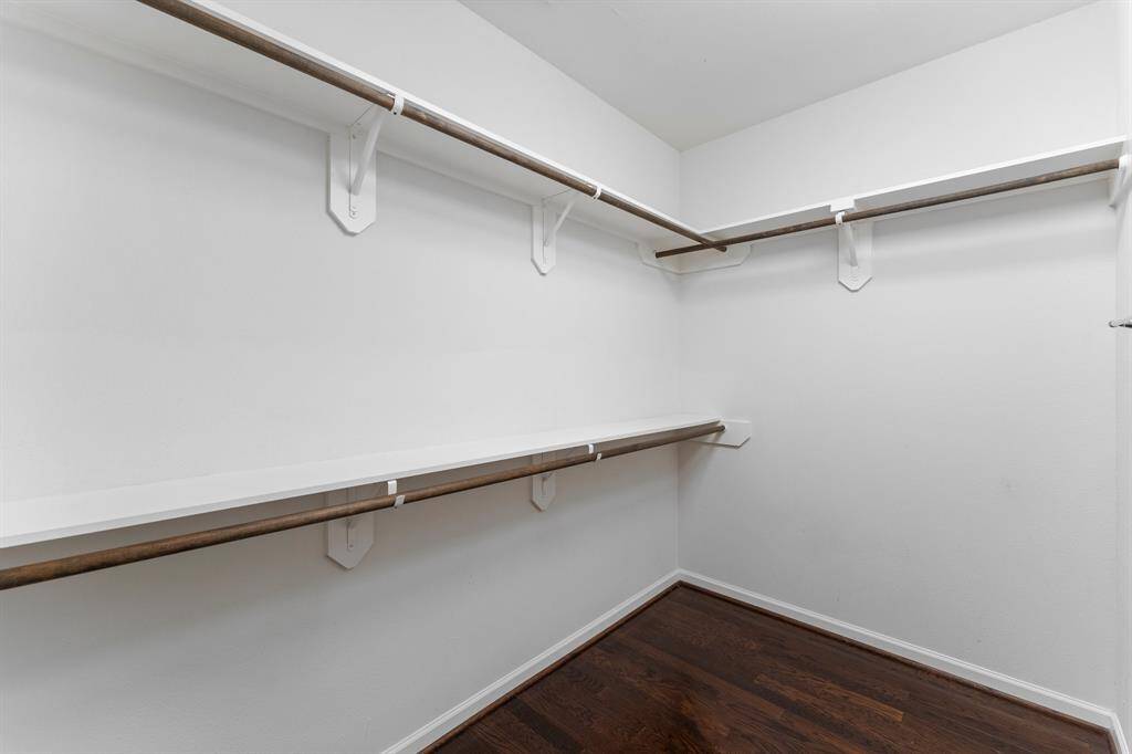 Spacious walk-in closet features double hanging rods and hardwood floors for organized, stylish storage.