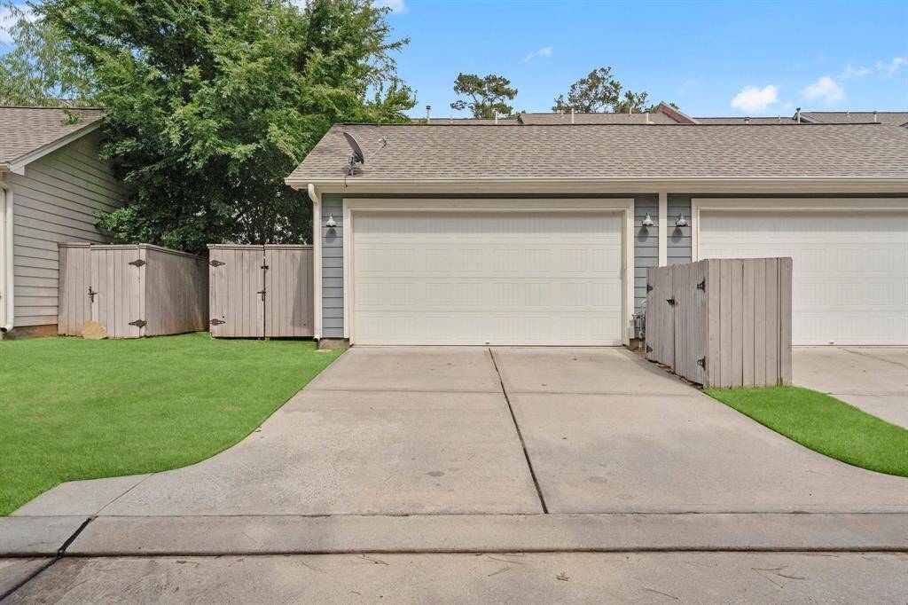 Detached rear-entry two-car garage with private gated access and additional storage sheds.