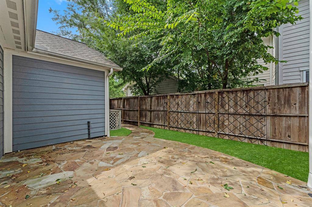 Side yard features a spacious flagstone patio and artificial turf, ideal for low-maintenance outdoor enjoyment.