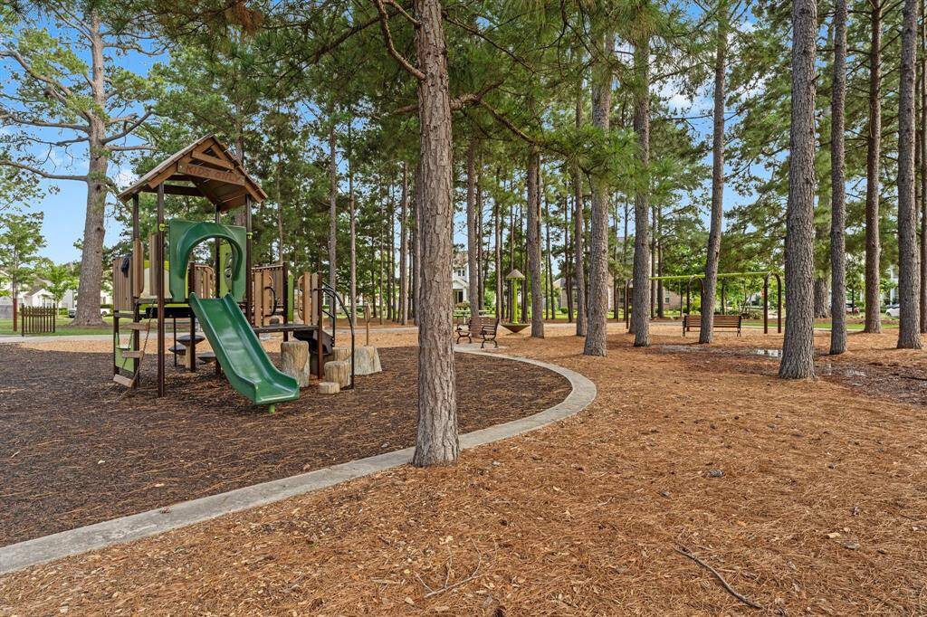 Enjoy a well-maintained community playground nestled among tall pines, complete with swings, slides, and shaded seating areas.