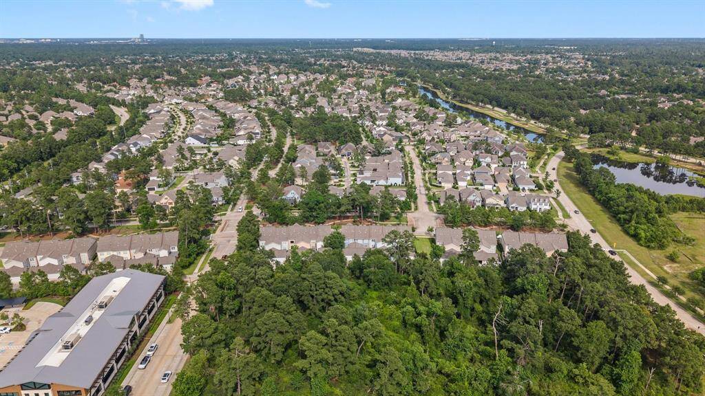 Aerial view of a beautifully planned, tree-lined community featuring scenic walking paths, tranquil ponds, and charming residential streets.