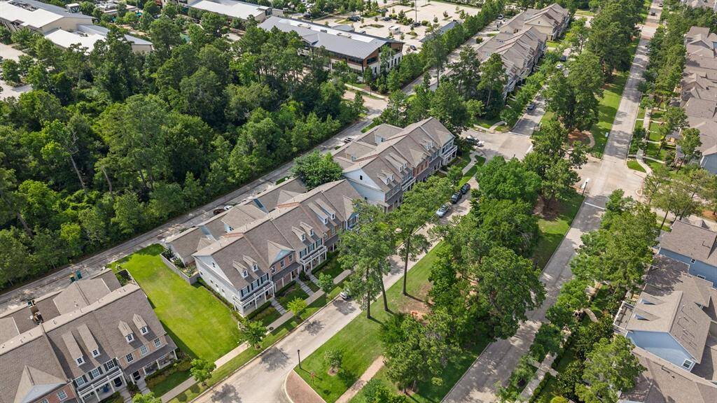 Aerial perspective of charming townhomes nestled along a tree-lined street with greenbelt views and convenient access to nearby shops and amenities.