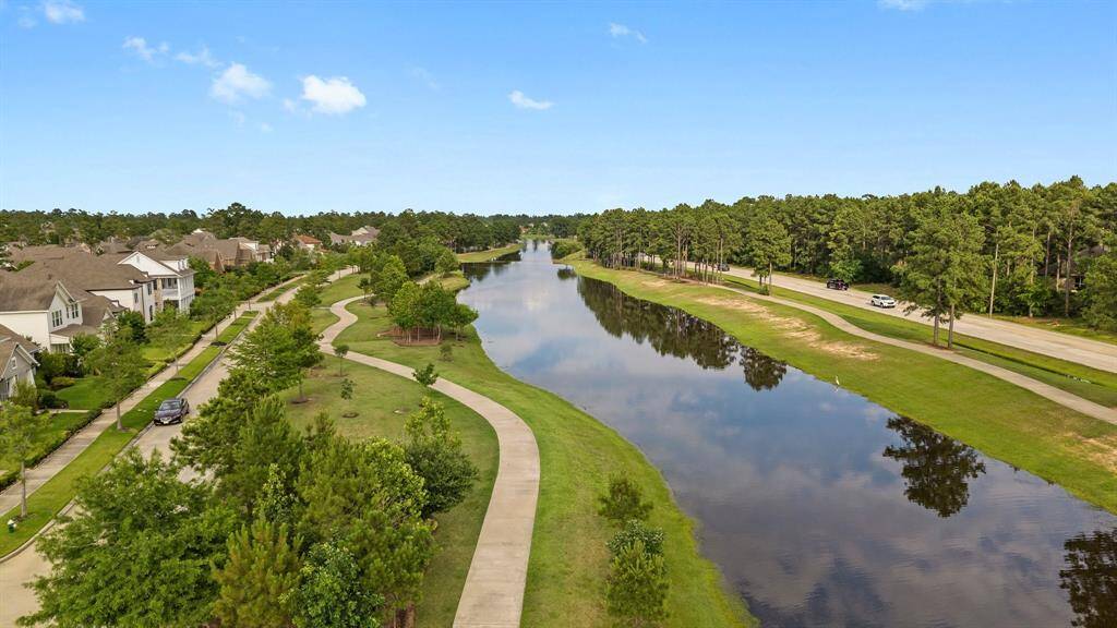 Scenic aerial view of tranquil walking trails and a peaceful waterway surrounded by lush greenery and beautiful homes.