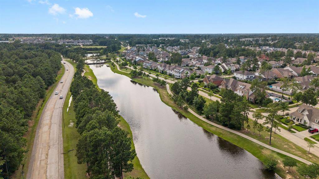 Aerial view showcasing a serene waterfront trail winding through a beautifully maintained residential community surrounded by lush greenery.