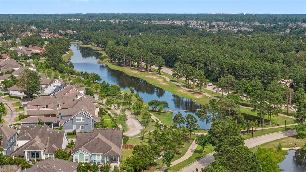 Beautiful aerial view showcasing serene waterfront walking trails, lush greenery, and charming residential streets nestled beside a tranquil canal.