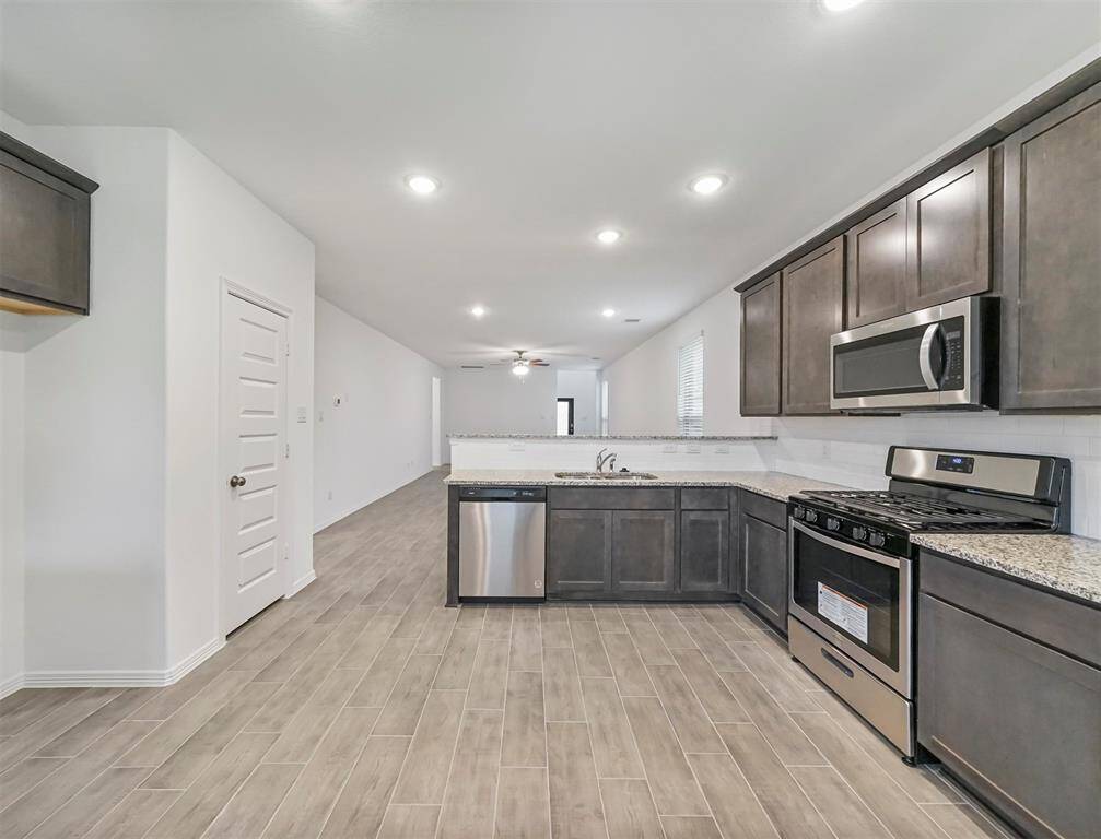 An additional view of the Gourmet Kitchen accompanied with tile flooring, handsome cabinetry, and extended breakfast bar for multiple cooks in the kitchen