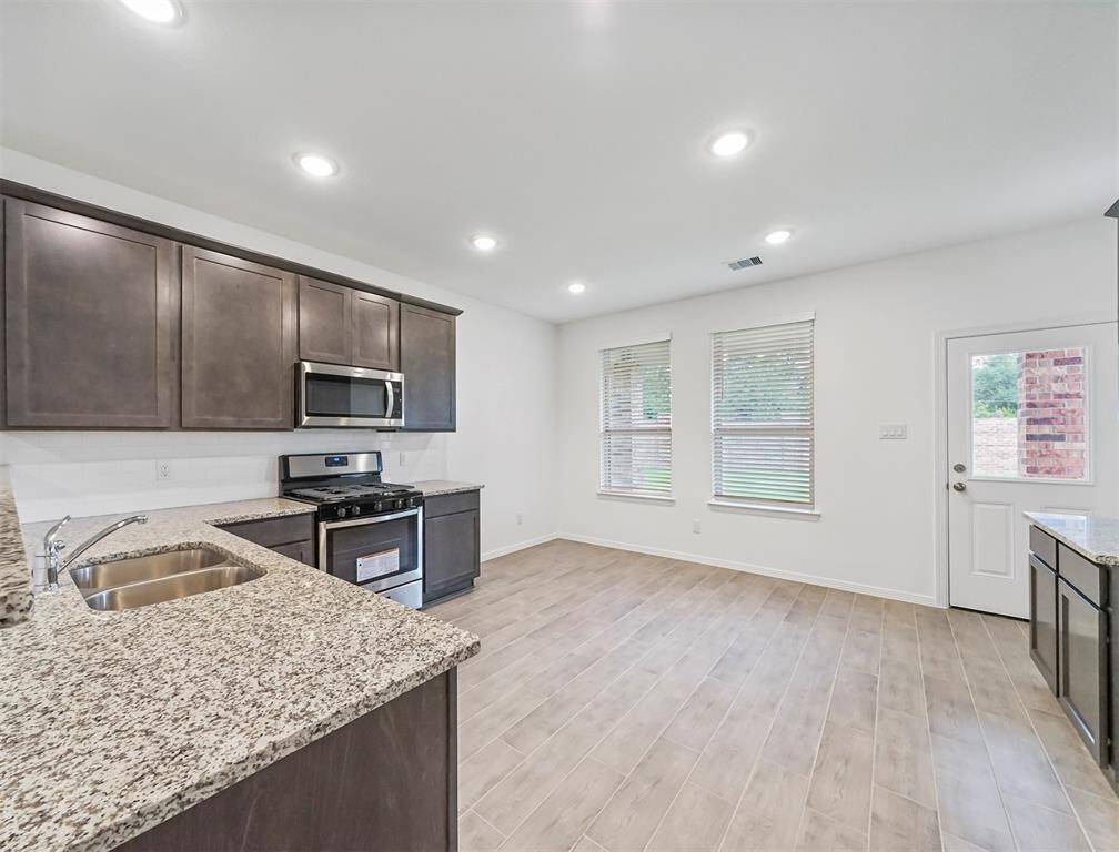 A view of the Gourmet Kitchen and Blissful Breakfast Nook featuring natual lighting from windows and easy access to the covered patio out back.
