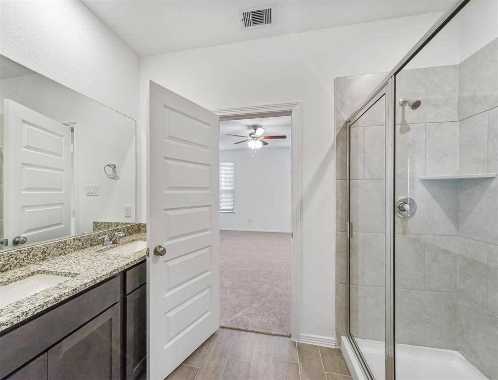 Primary Bath Oasis offers terrific tile flooring, granite countertops with handsome cabinetry, and glass enclosed shower with tile surround.