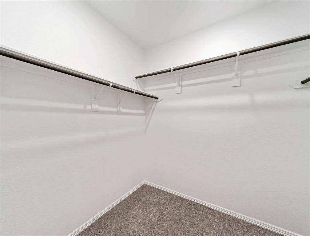 A look into the Primary Bathroom Spacious Walk-in Closet that offers plush carpeting and plenty of shelf space for holding your entire wardrobe!