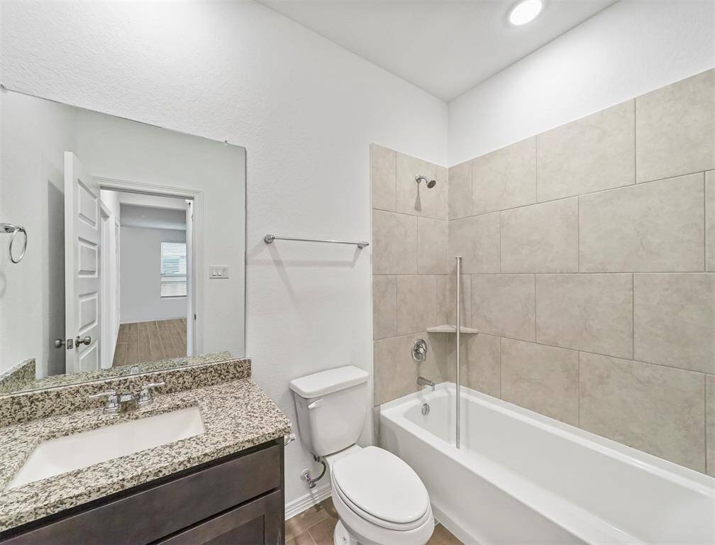 Secondary Bathroom with tile flooring, granite countertops, and tub and shower combination with tile surround.
