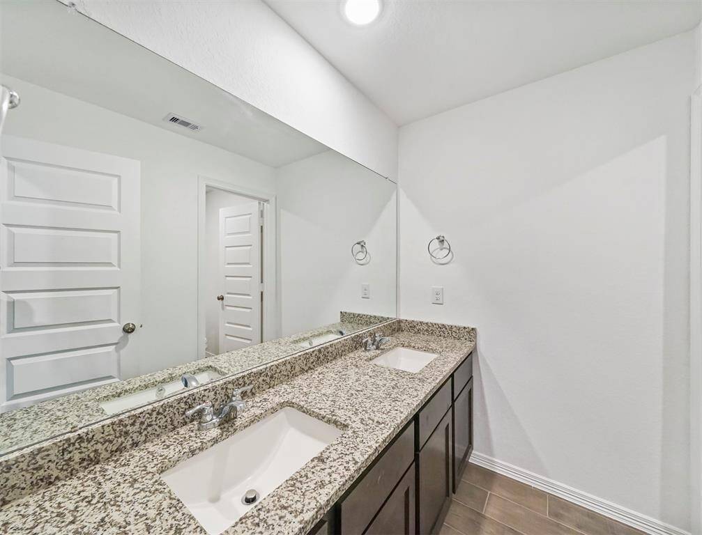 Serene Secondary Bathroom features granite countertops, double sinks and oversized mirror.
