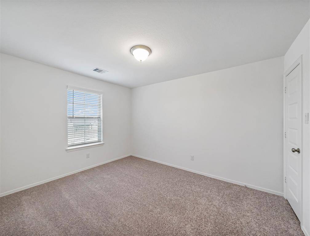 A look into another Splendid Secondary Bedroom that offers plush carpeting, natural lighting from window, and access to a spacious closet.