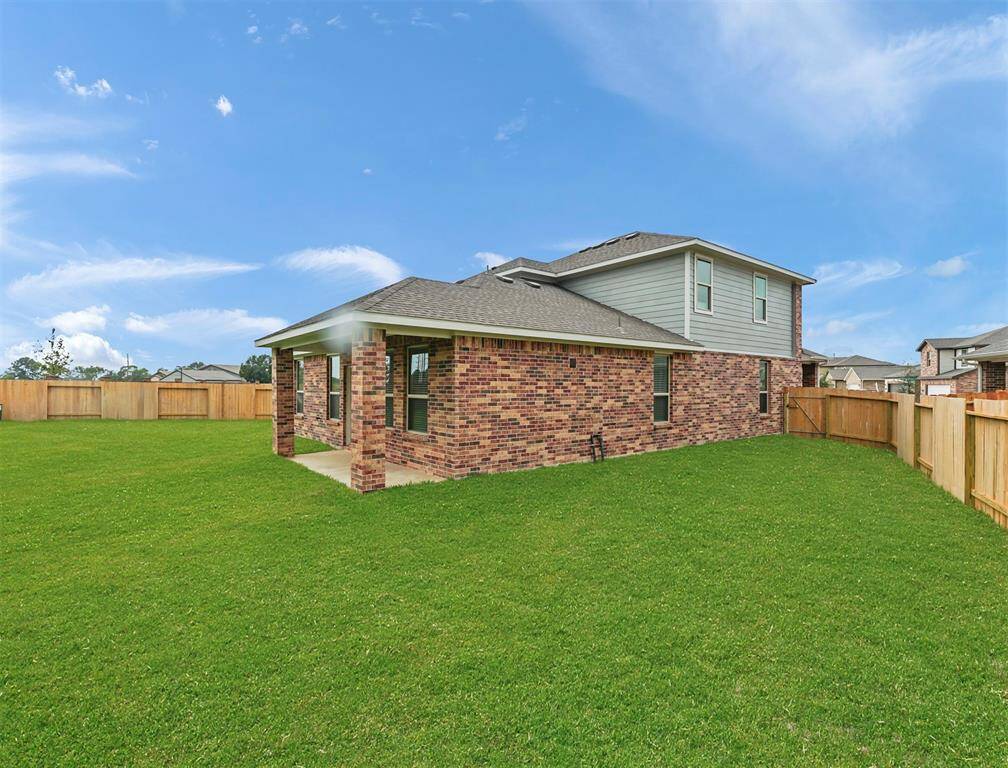 A view from the backyard showcasing the charming covered patio and abundance of yard space to utilize and make your own oasis!
