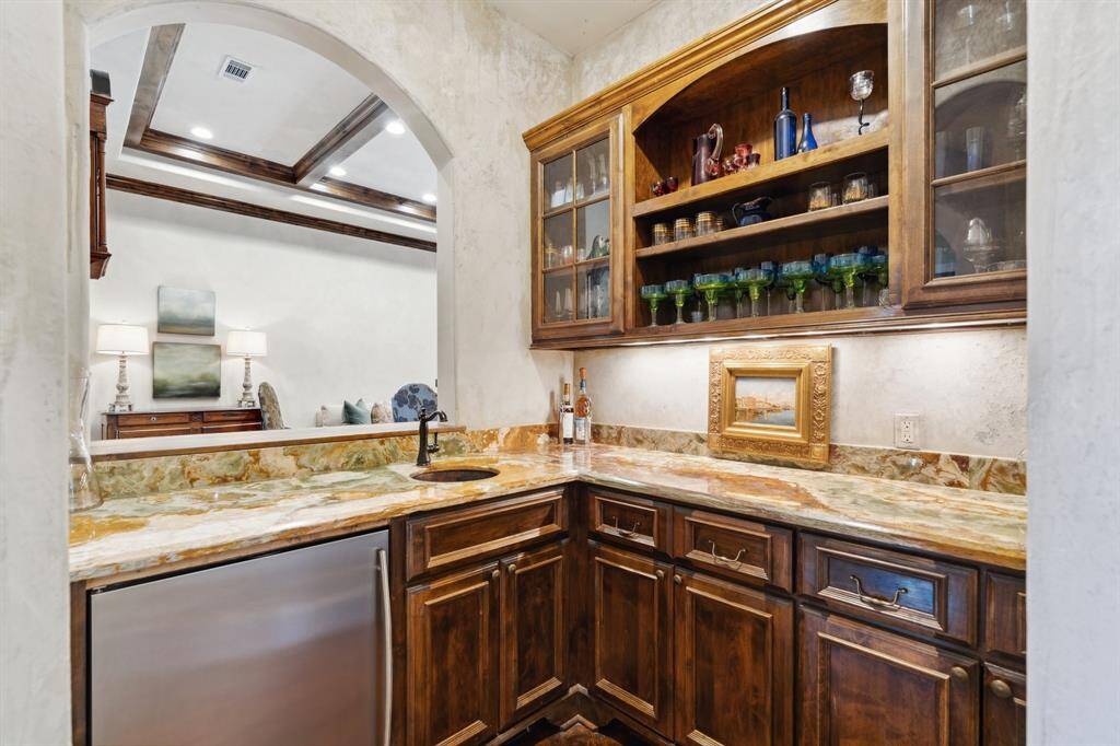 The Wet bar features Antiqued marble countertops, under cabinet lighting, and Plaster faux painted walls. The area has an arched opening to Living room.