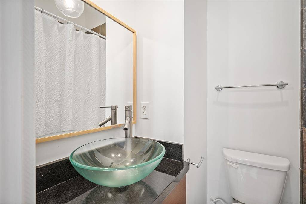 Stylish secondary bathroom featuring a unique glass sink, adding a modern touch and creating an elegant, contemporary look.