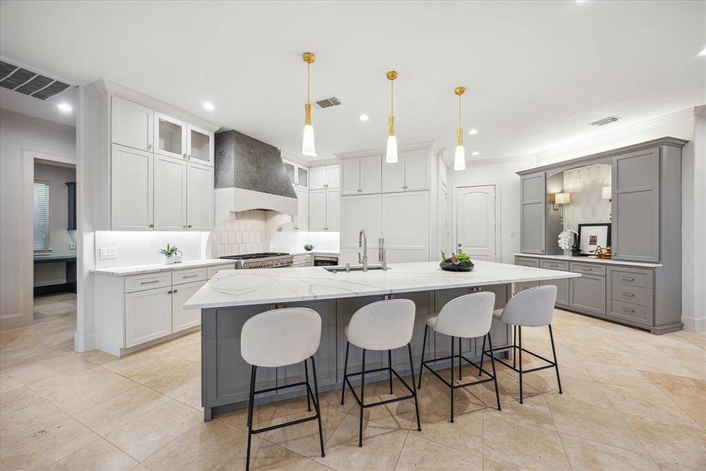 Beautifully remodeled to the studs, this stunning kitchen features custom cabinetry, designer quartz countertops, Ann Sacks tile backsplash, and an oversized island. Outfitted with Thermador Professional appliances, and a built-in beverage bar.