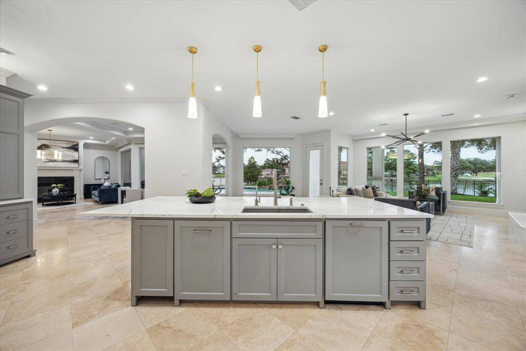 The expansive island serves as the heart of the home, offering seating for 6–8, abundant storage, and striking quartz countertops. Custom-built cabinetry, under-cabinet lighting, and premium Acera Bella hardware elevate both function and style.