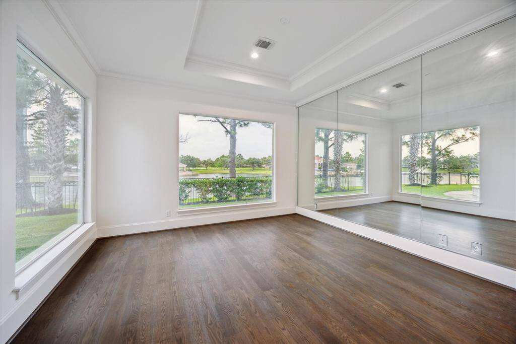 Located on the first floor, this spacious secondary bedroom offers privacy and comfort with serene views of the pool and lake. Featuring oak wood flooring.