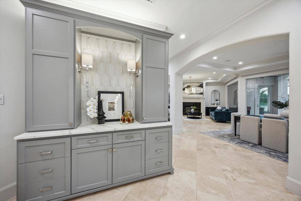 Conveniently located between the kitchen and dining room, this custom-built bar features elegant cabinetry, quartz countertops, and ample storage.