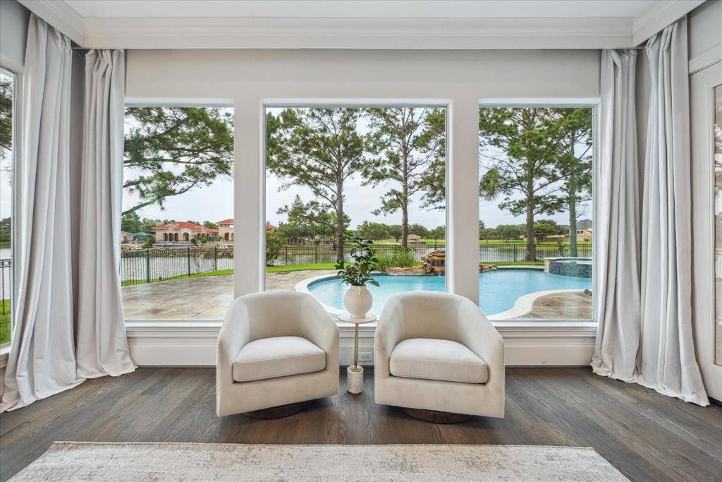 The sitting area offers a tranquil spot to unwind, framed by large windows showcasing sweeping views of the pool and lake.