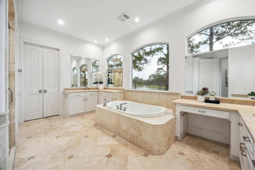 Designed for relaxation, the primary bath features a frameless glass shower with rainfall showerhead, a deep soaking tub with handheld massager, and high-end chrome fixtures throughout.