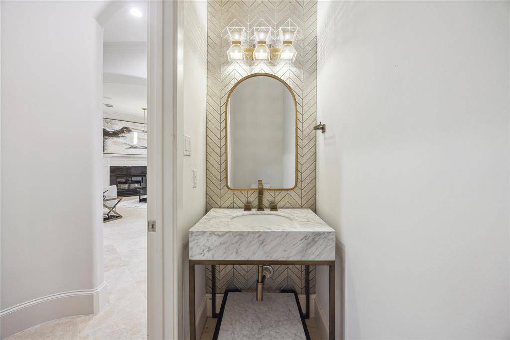This elegant powder bath features iridescent Ann Sacks wall tile, a boutique brass and quartz vanity, a custom light fixture and mirror.