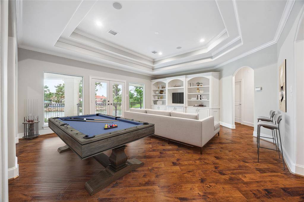 This spacious upstairs game room features custom built-ins for added storage and display, with double doors leading to a private balcony overlooking the lake.     *This photo has been virtually staged