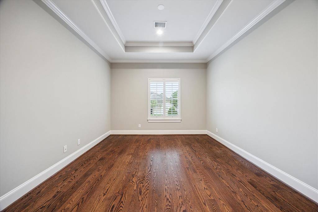 This generously sized bedroom features soft, neutral paint tones and abundant natural light, creating a fresh and airy atmosphere.