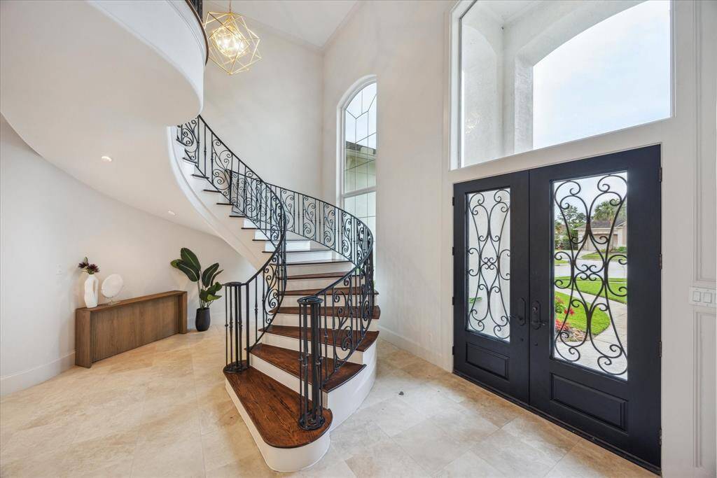 A soaring two-story foyer welcomes you with a dramatic sweeping staircase, elegant travertine floors, and designer lighting, setting the tone for the luxurious interiors that follow.