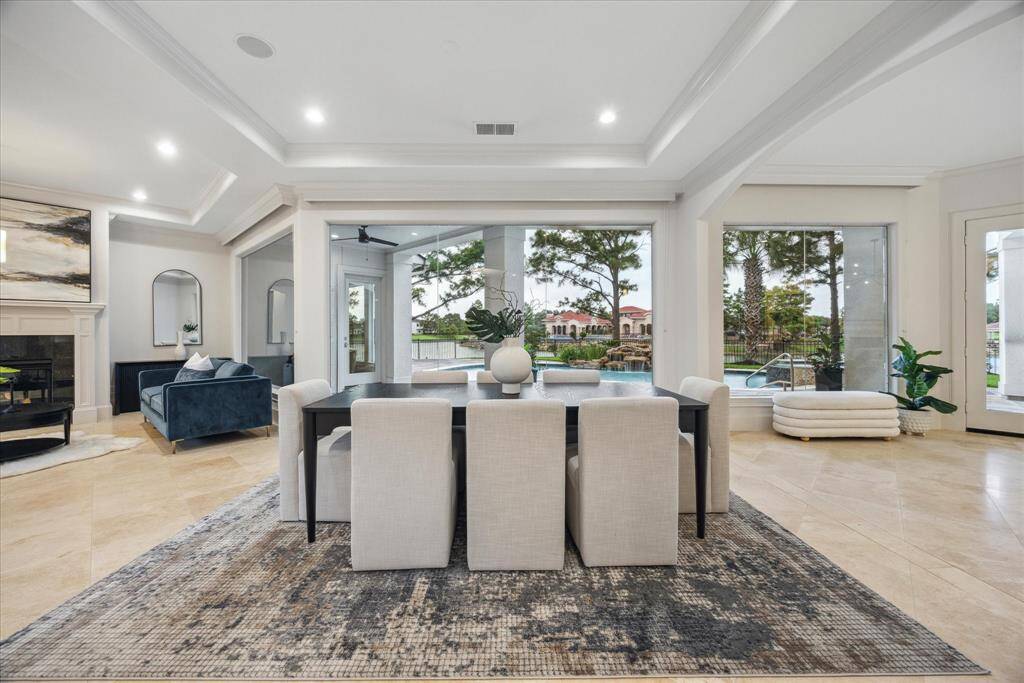 The formal dining room features a wall of windows that frame serene views of the pool and lake, creating a stunning backdrop for gatherings both intimate and grand.