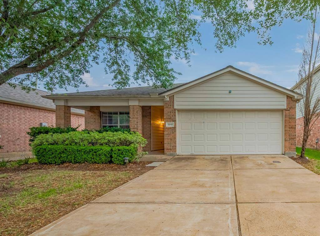 Charming single-story home with a brick facade, two-car garage, and a welcoming front porch. The driveway and mature trees add to its curb appeal.