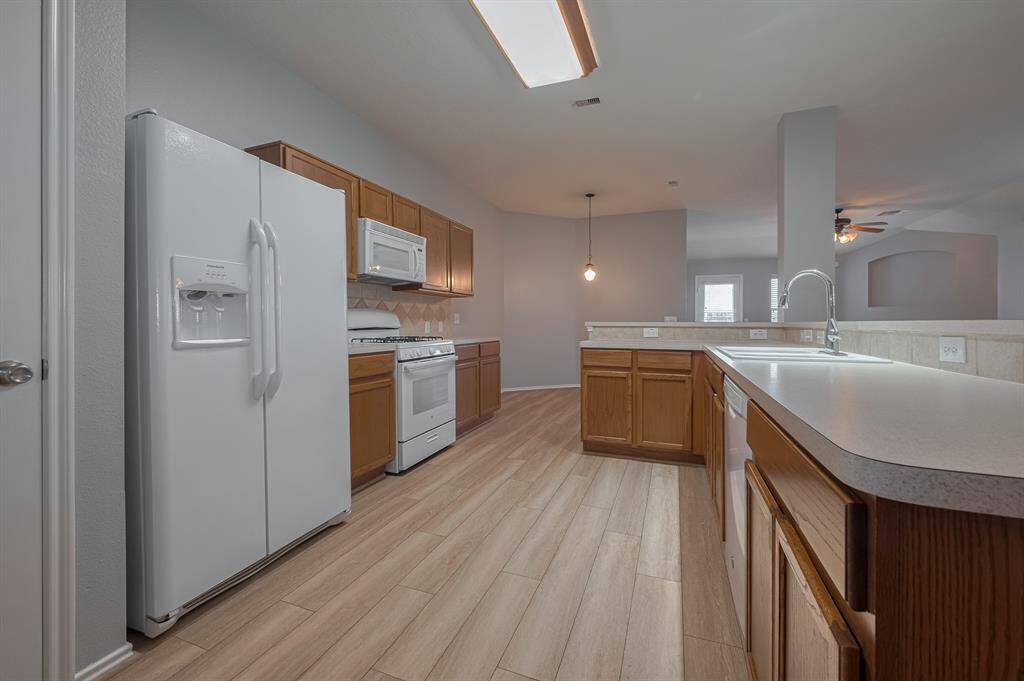 This spacious kitchen features modern appliances, ample counter space, and wooden cabinetry. It has an open layout with a view into the adjacent living area, ideal for entertaining.